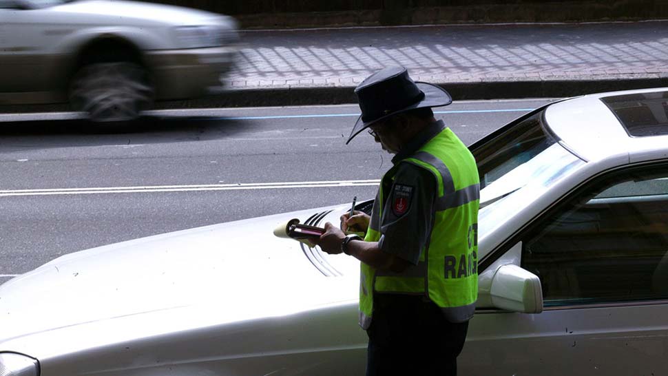 A parking inspector issues a ticket to a car parked on Macquarie Street in Sydney's CBD. (SMH Wade Laube)