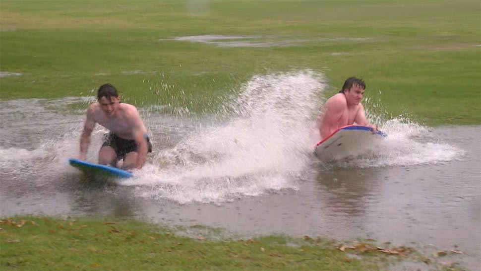 Two men play on boogie boards on a flooded Chiswick oval. (9News)