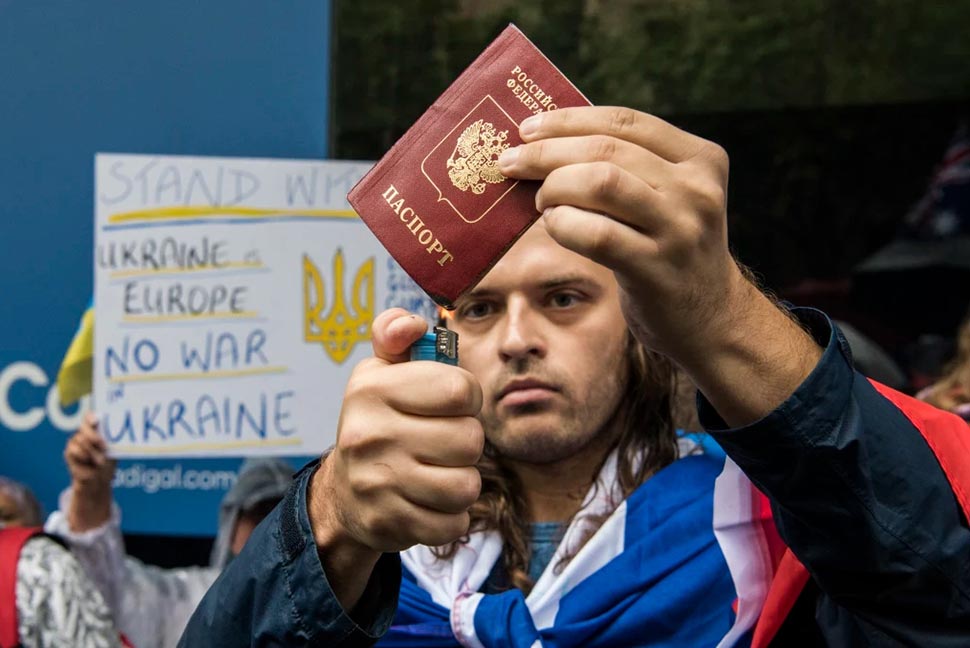 A man draped in the Russian flag attempts to burn a passport during the Stop War in Ukraine rally.CREDITSTEVEN SIEWERT