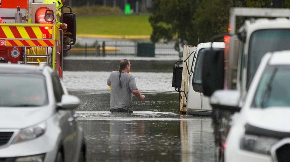 A man wades through flood waters back to his home from a fire truck at Windsor on the outskirts of Sydney. (AP)