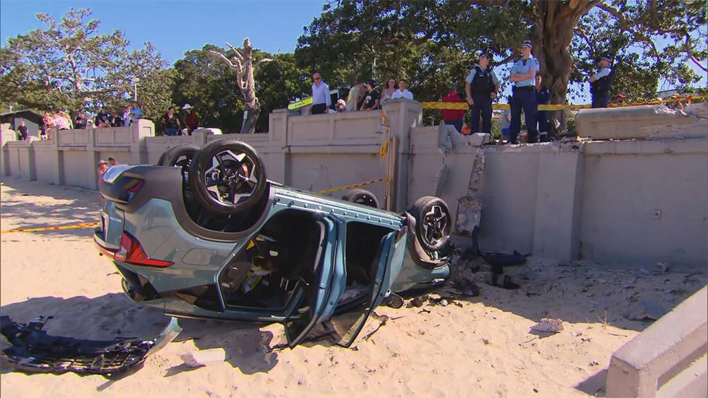 The car crashed through a concrete wall onto the busy beach. (9News)