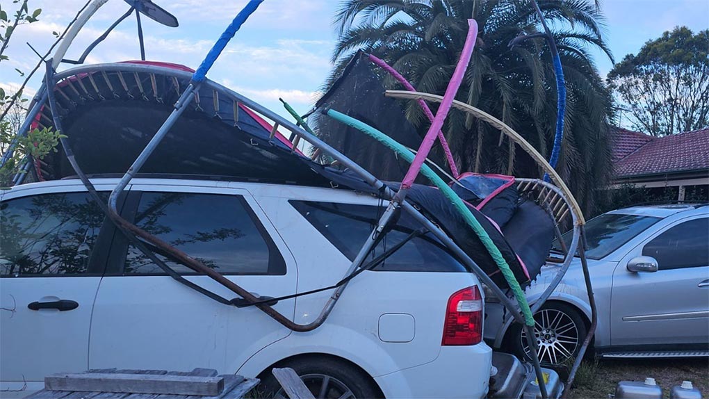 An overturned trampoline was blown onto parked cars. (2GB)