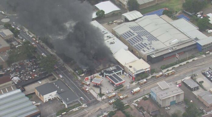 자동차 수리점 화재, 시드니 서부에서 출퇴근 시간 지연 유발 Up to 18 firetrucks and more than 60 firefighters are fighting the fire at a factory next to a petrol station and furniture warehouse in Stubbs Street, Auburn in Sydney's west. (Nine)