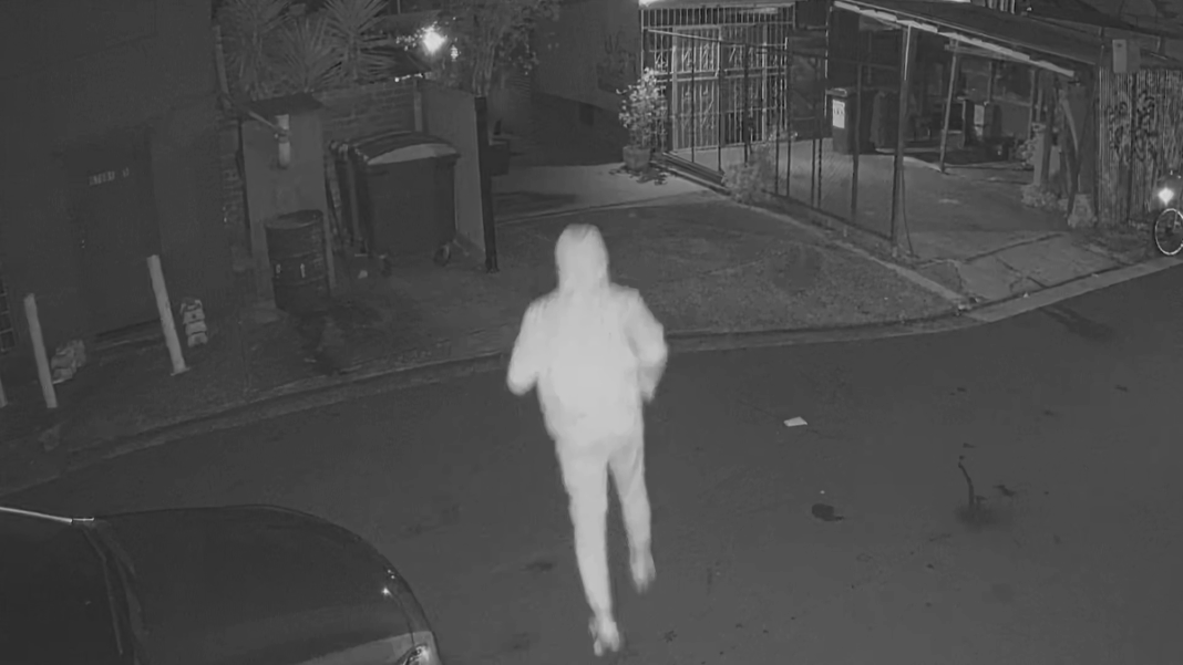 At the same location 24 hours earlier, a hooded figure is seen running in and out before the shop goes up in flames. (Nine)