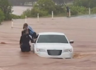 퀸즐랜드 번다버그 인근 홍수 차량서 어린이 구조 Footage appears to show a child being pulled from a car by police on a flooded causeway at Bargara. (Facebook)_9NEWS