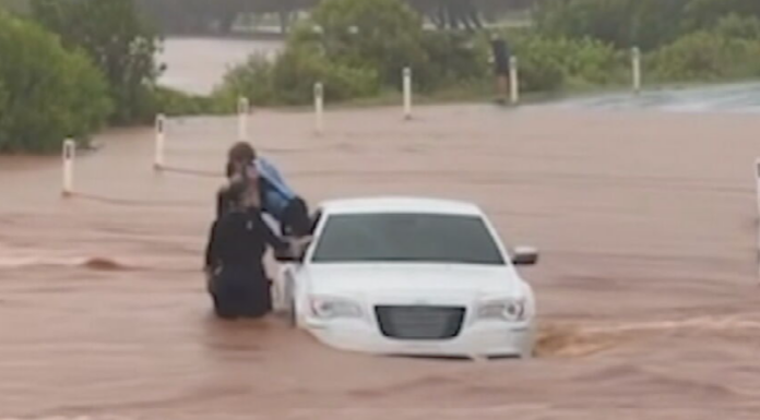 퀸즐랜드 번다버그 인근 홍수 차량서 어린이 구조 Footage appears to show a child being pulled from a car by police on a flooded causeway at Bargara. (Facebook)_9NEWS